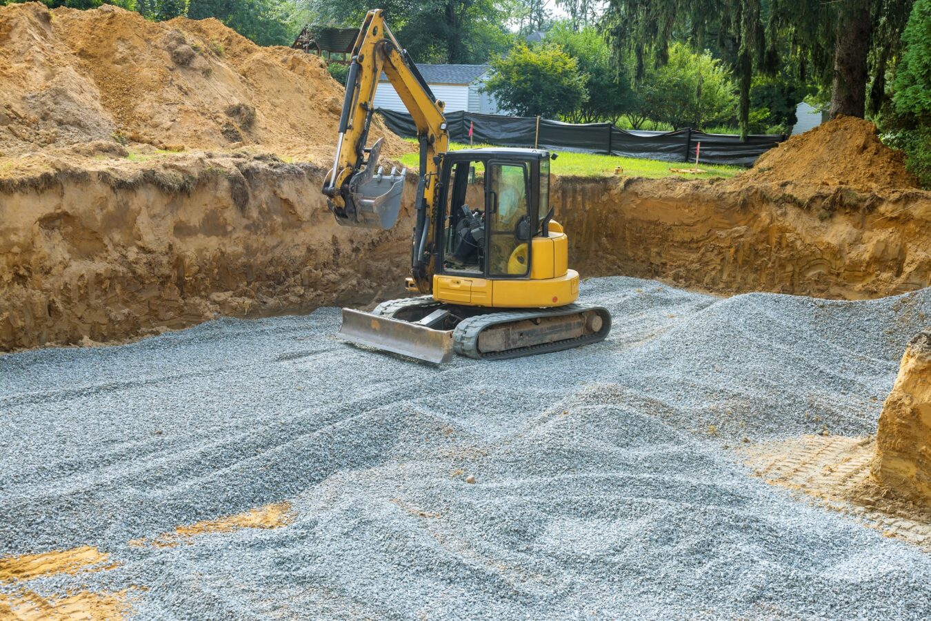 An excavator fills irregularities in excavations with granite rubble base to serve as foundation for