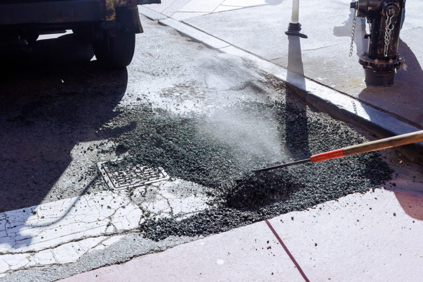 Fresh asphalt construction resurfacing a bad road in city